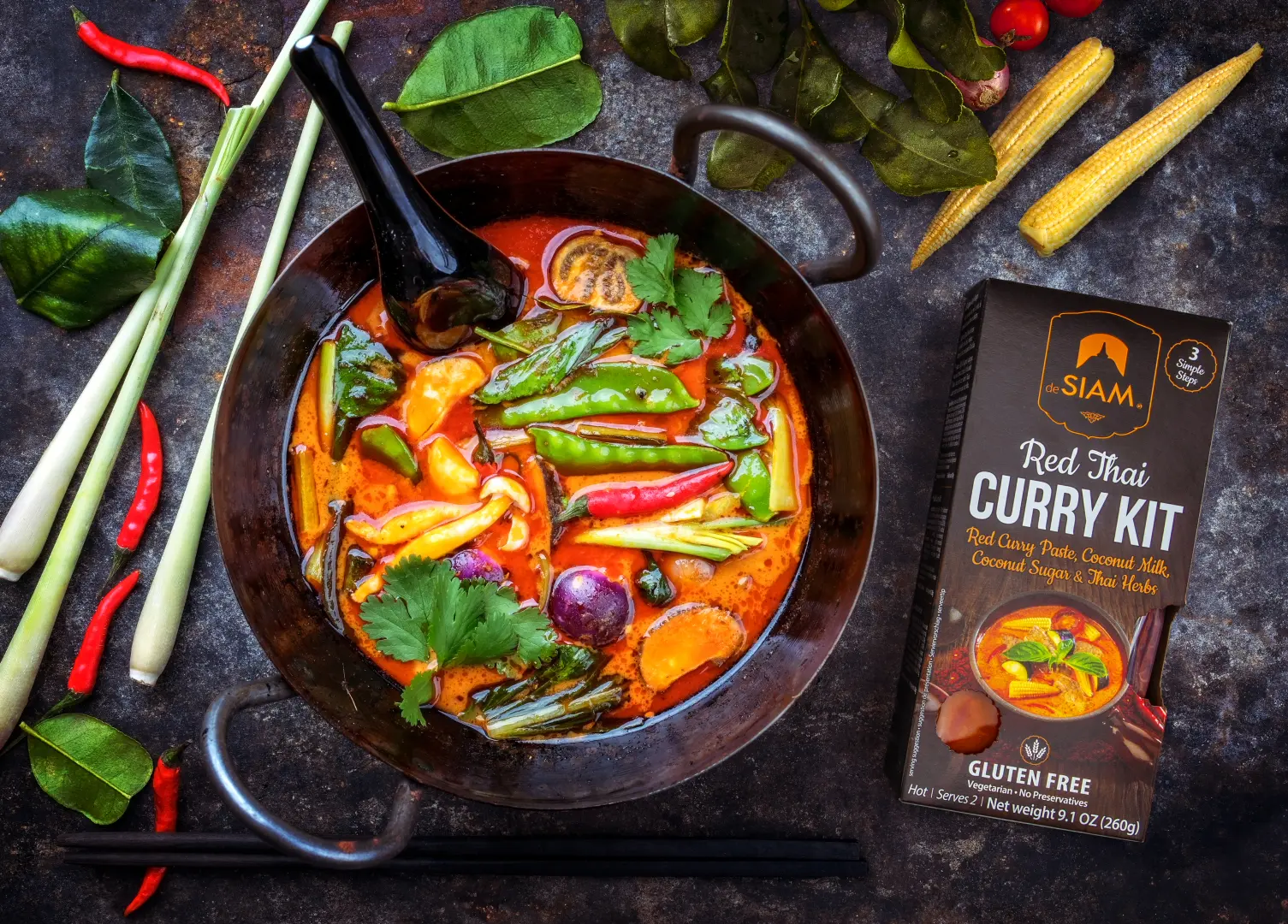 In einer Pfanne thailändisches Curry mit roter Zwiebel, Pilze, Tomate, rote Chili Schoten, Zuckerschoten, Sellerie, Maiskölbchen, Frühlingszwiebel, Petersilie, Lorbeerblätter